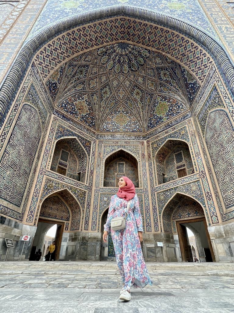 Asheera beneath an ornate tiled arch during her travels